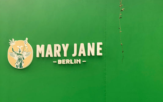 Logo der Mary Jane Berlin Messe auf grünem Hintergrund – mit stilisierter Berliner Siegesgöttin, Hanfblatt und Veranstaltungsname