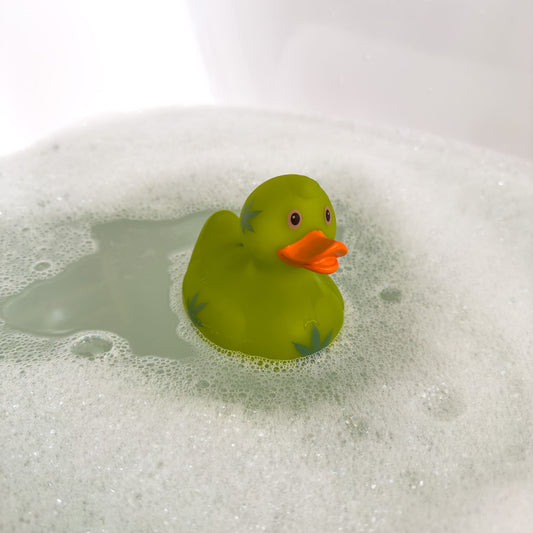 Grüne Badeente mit Blattprint schwimmt in einer mit Schaum gefüllten Badewanne