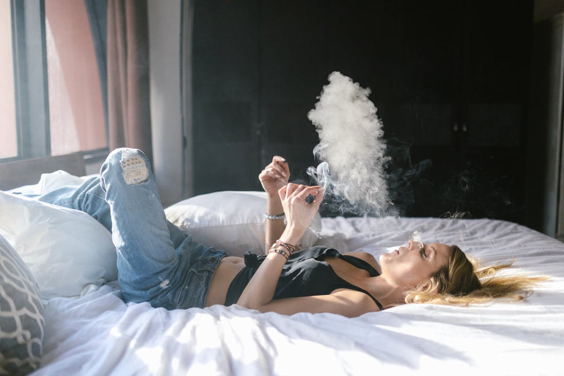Frau liegt entspannt im Bett und raucht – moderner Cannabis-Lifestyle