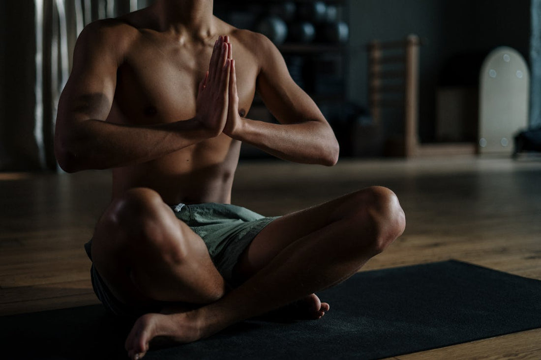 Junger Mann in sportlicher Meditation im Schneidersitz auf einer Yogamatte – Symbolbild für Regeneration, Fokus und CBD im Sport