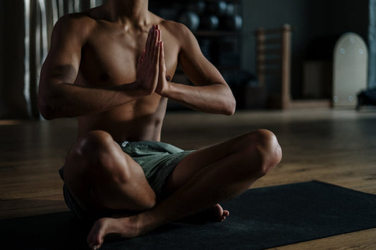 Junger Mann in sportlicher Meditation im Schneidersitz auf einer Yogamatte – Symbolbild für Regeneration, Fokus und CBD im Sport